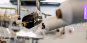 Rolls of PolyLon36 yarn on the manufacturing line, illustrating the sustainable and durable material used for The Sox Factory's high-performance custom socks.
